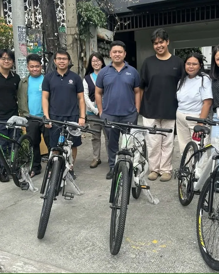 Volunteers and beneficiaries with a row of donated bicycles